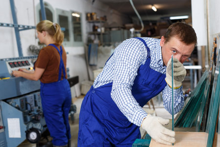 Experienced male glazier during daily work in glass factoryの写真素材