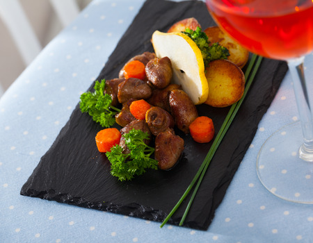 Delicious fried chicken hearts served with baked vegetables and fresh pear  at plateの写真素材
