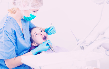 Teen girl getting dental treatment by professional dentist in modern dentistryの写真素材