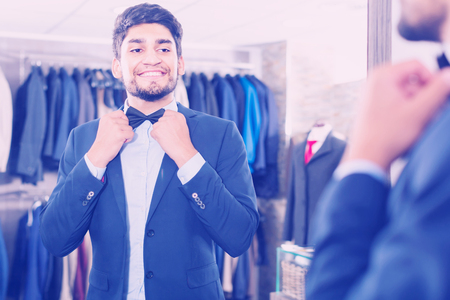 Male is trying on butterfly in front of the mirror in men's shop.の写真素材