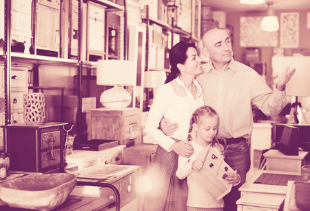 Family with small girl choosing furniture for house in showroomの写真素材
