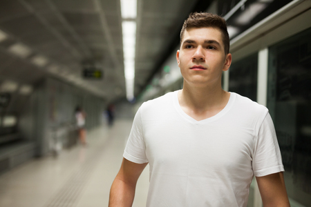 Portrait of young confident male passenger in casual clothing on underground platform with copycpaseの写真素材