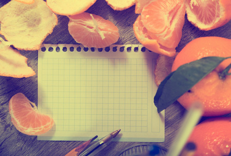 Leaf notebook with writing utensils surrounded by tangerinesの写真素材