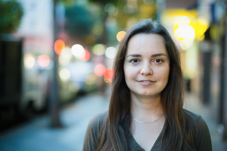 Closeup on cheerful adult female outdoors on summer evening in townの写真素材