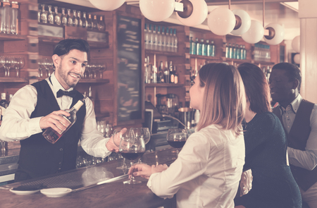 Modern girl and man are relaxing near bar counter and drinking alcohol in restaurantの写真素材