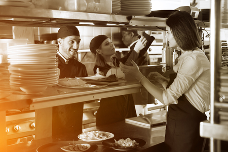 Young kitcheners are taking order from female waiter in restaurantの写真素材