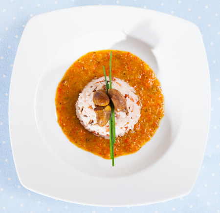 Top view of fried chicken hearts served with boiled rice and tomato cream sauce on white plateの写真素材