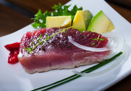 Appetizing light roasted tuna fillet served with avocado and greensの写真素材