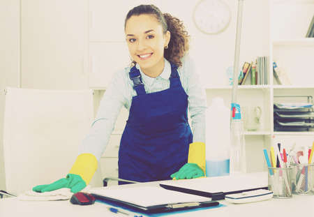 Pretty woman in uniform with supplies cleaning in officeの写真素材