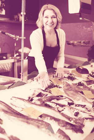 positive american shop female stuff selling chilled on ice fish in supermarketの写真素材