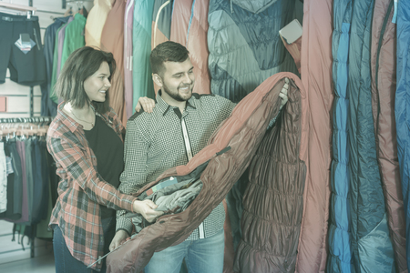 Young couple choosing new sleeping bag in sports equipment storeの写真素材
