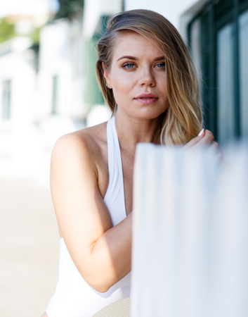 Closeup of young female in swimsuit posing near hotel fence at sea shoreの写真素材