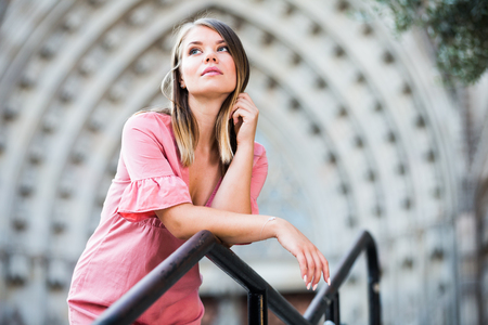 Young romantic woman looking around and walking on old town streetの写真素材
