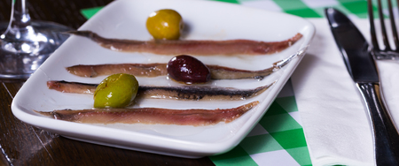 Photo of herrings with olives on the plate in the restaurant.の写真素材