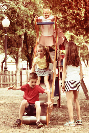 Cheerful boy and girl play games and running around sliding toy in parkの写真素材
