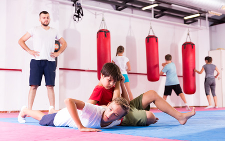 Kids in sportswear exercising self-protection techniques in pair during class at gymの写真素材