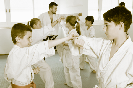 Positive teenagers practicing new karate moves in pairs in classの写真素材