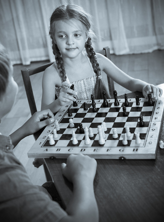 Brother teaching his little sister playing chess at homeの写真素材