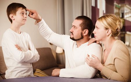 Serious woman with man parenting son at homeの写真素材