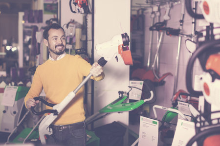 Guy deciding on best hedge cutter in garden equipment shop