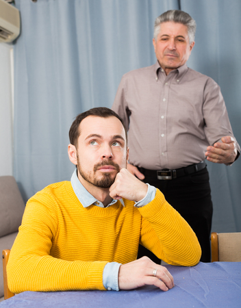 Adult father guides and teaches his son at table at homeの写真素材