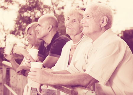 Postive american mature people with plastic cup standing in the parkの写真素材