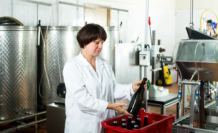 Female worker sorting wine bottles at sparkling wine factoryの写真素材