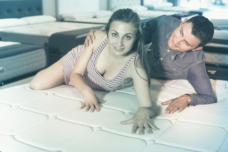 Young family couple choosing mattress  in  furniture storeの写真素材