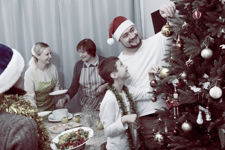 Happy family preparing for celebration of New Year, decorating Christmas tree and setting tableの写真素材