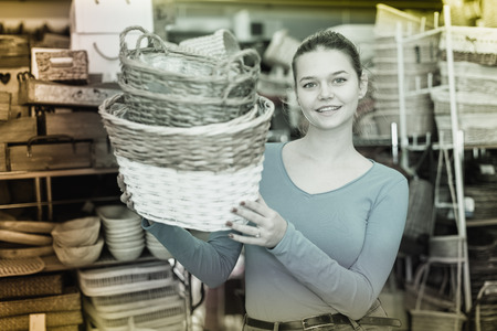 Female teen standing with wicker basket in decoration and furniture storeの写真素材