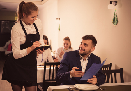 Woman waiter is taking order from client in restaurante indoor.の写真素材