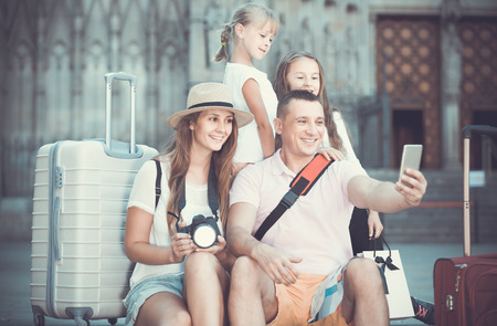 Happy french  family of tourists making selfie during travelling on European cityの写真素材