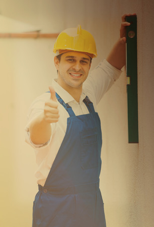 european builder posing with spirit level at construction siteの写真素材