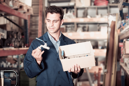 Portrait handsome male of 35-40 years old is choosing small details in boxes in the building storeの写真素材