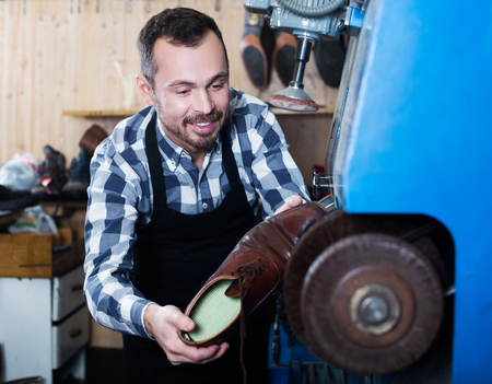 Portrait of male worker repairing shoe in specialized workshopの写真素材