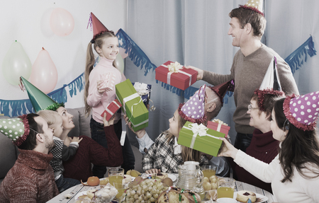 Family members presenting gifts to little girl during birthday partyの写真素材