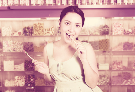 Young woman  sucking lolly  in candies shopの写真素材