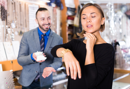 Positive female consumer trying gold bracelet in the jewelry shopの写真素材