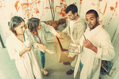 Group of young adults trying to get out of escape room stylized as medical room with traces of blood