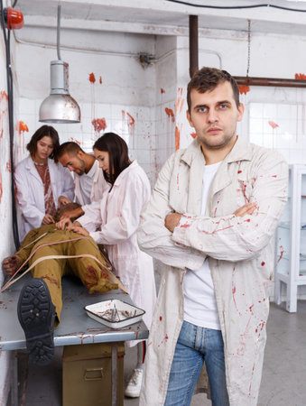 Portrait of focused guy with friends in escape room stylized as medical room with traces of blood