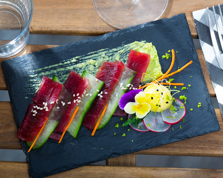 Tuna sashimi served on black board with fresh cucumber and avocado sauceの写真素材