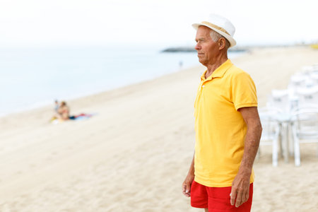 Lucky elderly man in a hat resting near ocean