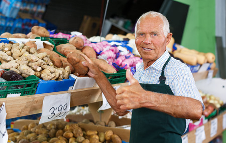 Successful elderly male owner of greengrocery shop giving thumbs up, recommending fresh productsの写真素材