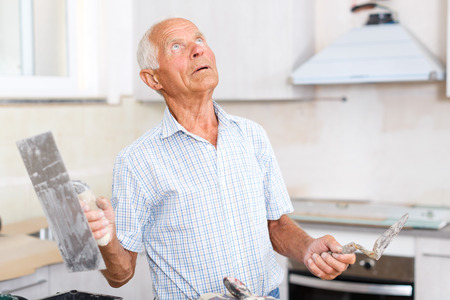 Senior man working on his house overhaul, determining scope of plastering works indoorsの写真素材