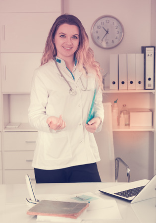 Portrait of young medical worker in medical center standing near the tableの写真素材