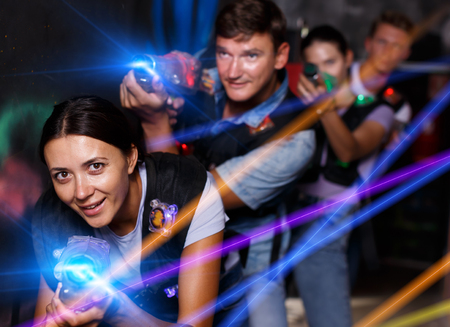 Group young emotional people with laser guns  playing laser tag  game together in dark corridorの写真素材