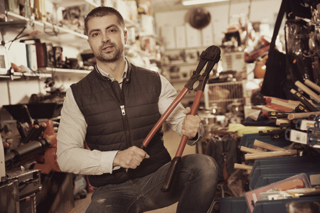 Glad positive  man is choosing new construction pliers in tools store.の写真素材