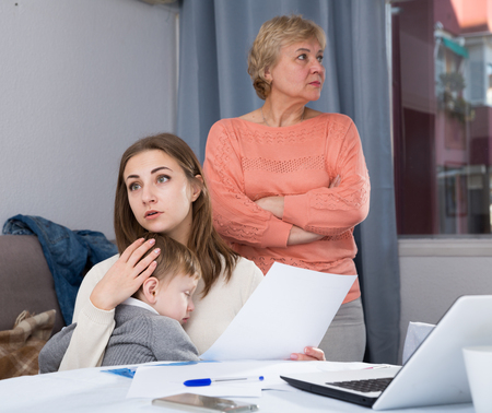 Outraged female are having disagreements with her mother for problems with filling documents at home.の写真素材