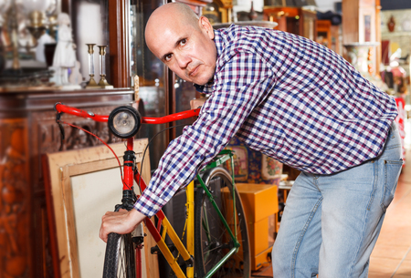 Interested adult male collector of vintage items choosing ancient things in antique storeの写真素材