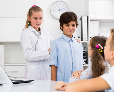 Young female doctor in uniform leading medical appointment with childrenの写真素材